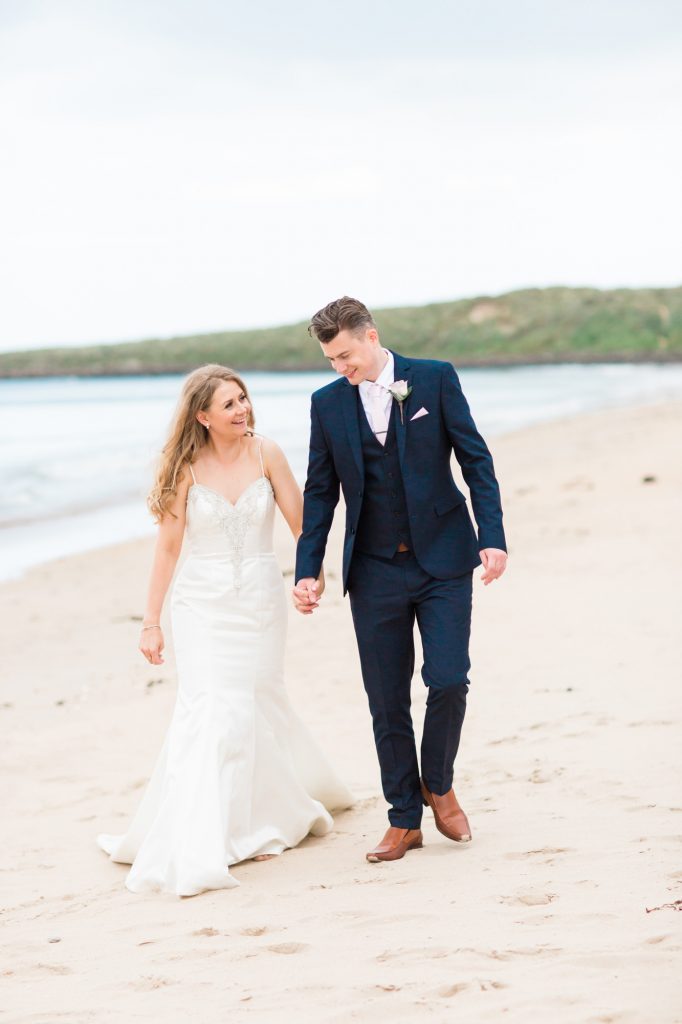 Groom walks with bride on beach